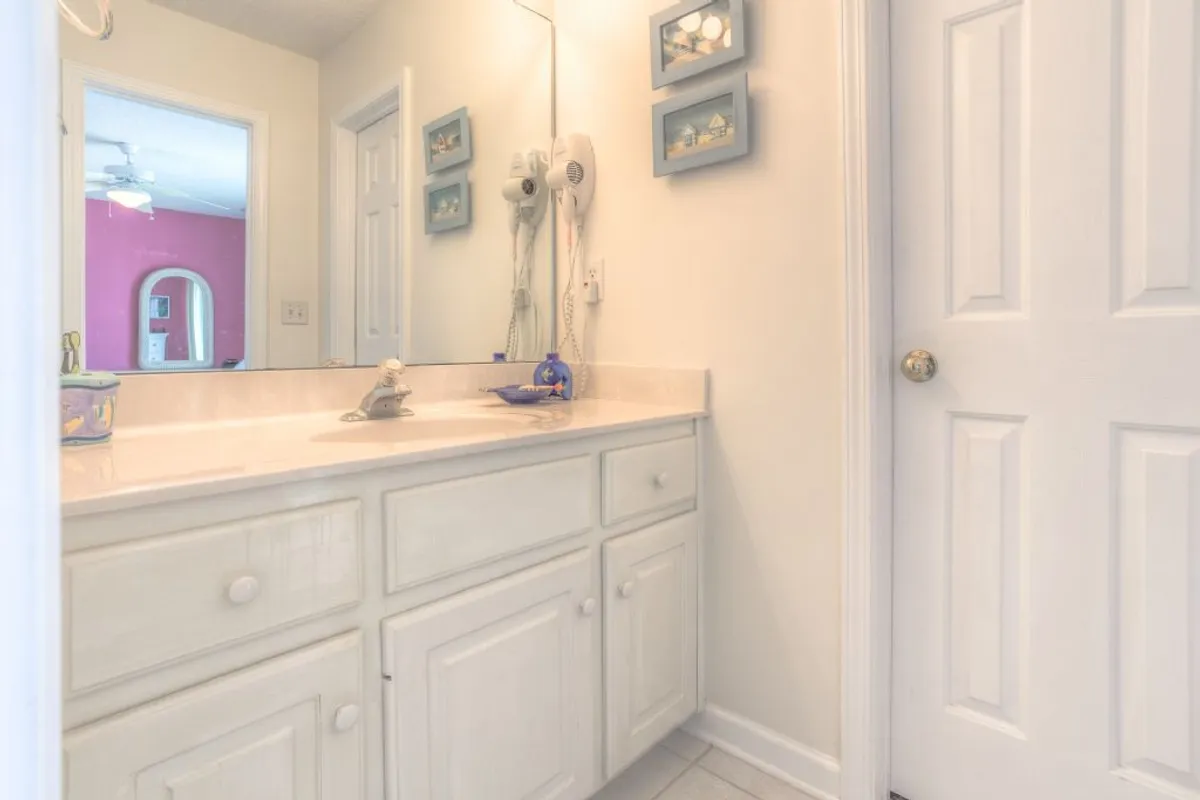 A well-lit bathroom features a modern vanity, a large mirror, and stylish picture frames. The atmosphere is inviting and fresh, ideal for self-care and quick preparations.